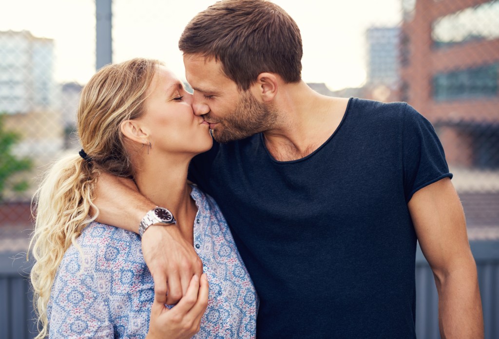 Young couple sharing a romantic kiss outdoors on an urban street